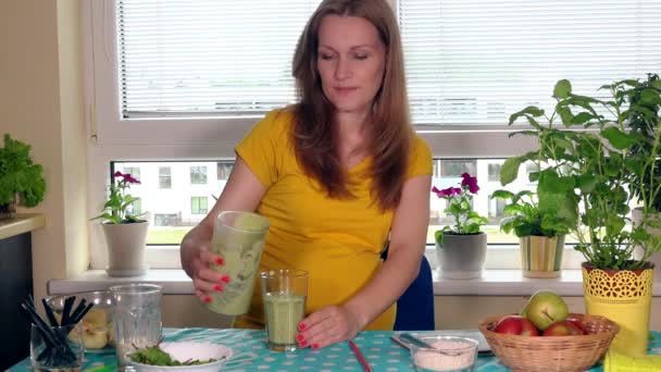 Бодрая беременная жена готовит здоровый коктейль и пьет его, глядя в камеру. — стоковое видео