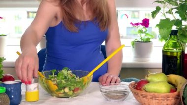 Bekleyen anne tuz dökün ve ekolojik sebze salatası cam kase içinde karıştırın