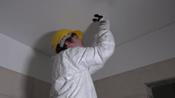 Hombre electricista con agujero de corte de sierra manual en el techo para la instalación de iluminación — Vídeos de Stock