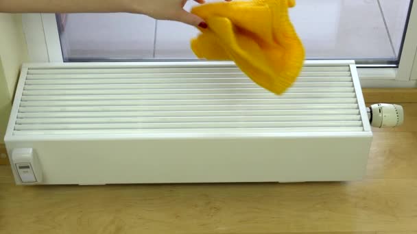 Жінка рука поклала жовтий шарф і червоні рукавички на радіатор вдома . — стокове відео