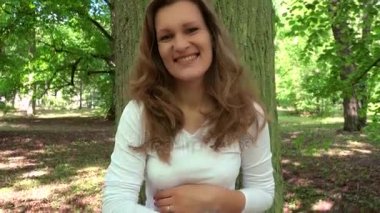 Gülümseyen hamile kadın kameraya ihale seyir büyük karnı stoke