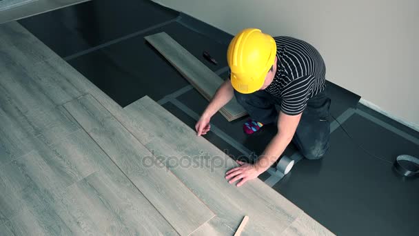 Professionele mannelijke werknemer met gele helm vloerplanken installeren — Stockvideo