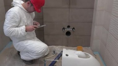 Yeni modern banyo tuvalet kase el mount üzerinde çalışan yetenekli tesisatçı adam