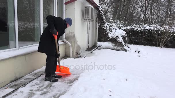 Man werknemer schone sneeuw van pad in de buurt van huis in winter park. 4k — Stockvideo