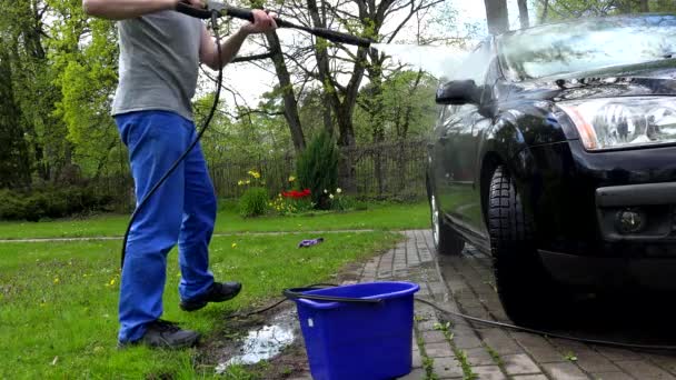 Travailleur masculin lave voiture avec jet d'eau de puissance en plein air . — Video
