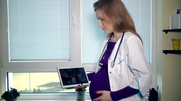 Grávida médico mulher acariciar barriga e olhando para ultra-som foto em comprimido — Vídeo de Stock