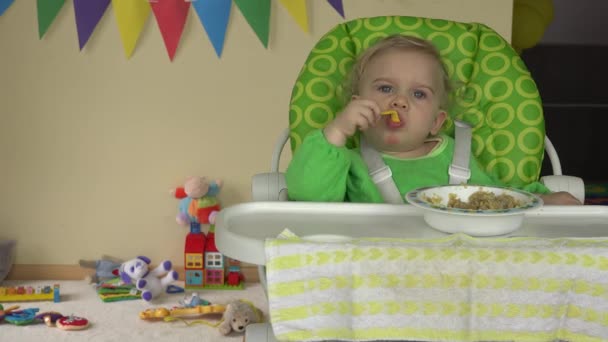 Baby zit in kinderstoel met lepel en plaat en speelgoed wachten op baby — Stockvideo