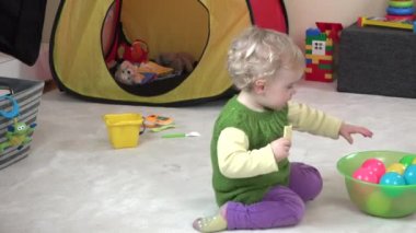 Yürümeye başlayan çocuk kız kurabiyeni ye ve oyun odası renkli topları ile oynamak.