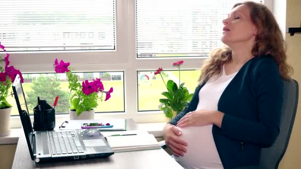 Κουρασμένος νεαρή έγκυο γυναίκα αναπαύεται στο χώρο της εργασίας. Γυναικείο χάδι τρυφερό κοιλιά — Αρχείο Βίντεο