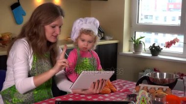 Anne ve tatlı kızı mutfakta tablet bilgisayar kullanarak portresi