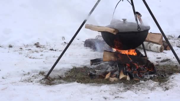 Tourist pot hang over fire in forest winter, over campfire. 4K — Stock Video