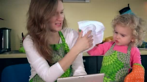 Грайлива мати з маленьким помічником розважається на кухні з планшетним комп'ютером — стокове відео