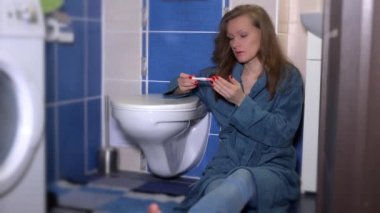 Hamilelik testi banyo dolabında yakın oturan bakarak pijama üzgün kadın.