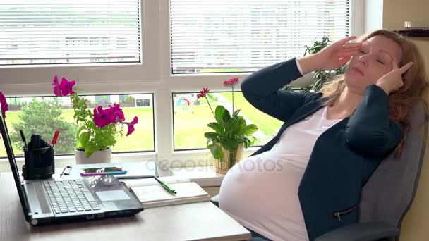 Agotado embarazada madre sintiendo dolor de cabeza sentado en la oficina . — Vídeos de Stock