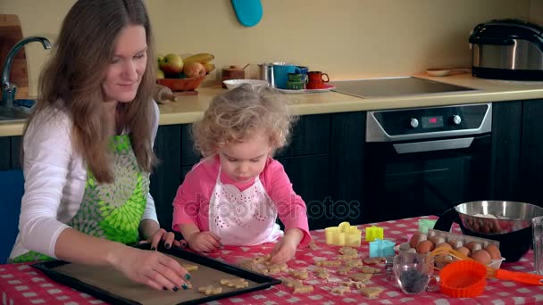 オーブン錫に小さな娘女の子場所クッキーと母 — ストック動画