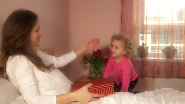 Дочь девочка подарить матери день рождения подарок в постели — стоковое видео