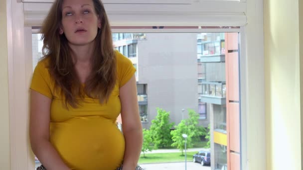 Frustrated pregnant woman call phone and shout sitting on window sill — Stock Video