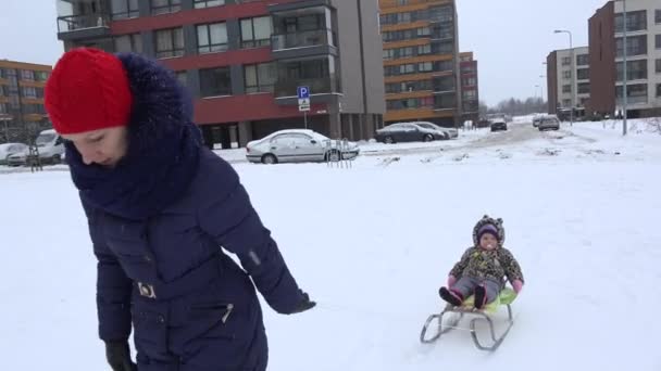 La madre tiró del trineo con la hija bebé en invierno en el parque. 4K — Vídeo de stock