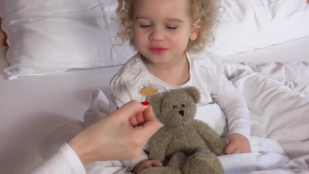 Η μητέρα ή ο γιατρός να δώσει ευχαρίστως toddler κορίτσι κουτάλι με ιατρική βιταμίνη — Αρχείο Βίντεο