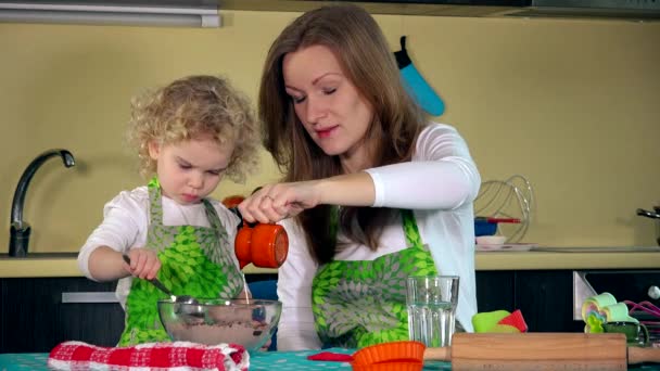 Douce petite fille mignonne apprend de maman comment faire du gâteau dans la cuisine à la maison — Video