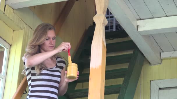 Mujer adulta pintando nuevo poste de columna de madera con pincel en escalera. 4K — Vídeo de stock