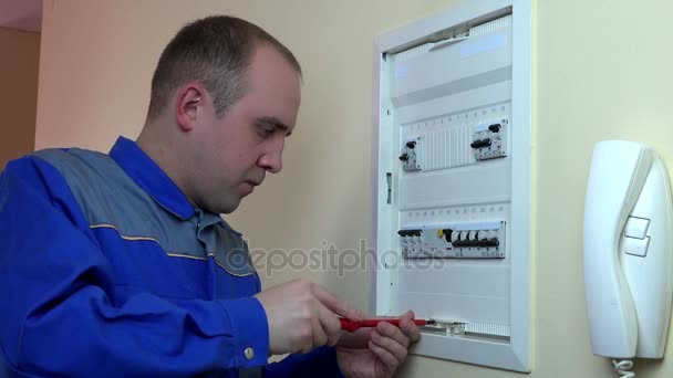 Чоловік електрик працює на вимикачі в клієнтському будинку. 4-кілометровий — стокове відео