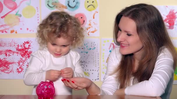 Glückliche kaukasische Frau und Kind legen Münzen in Sparschwein — Stockvideo