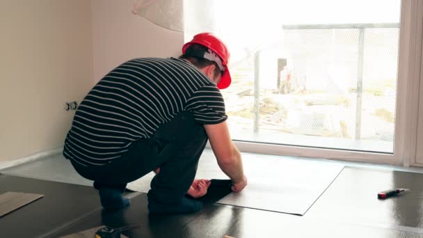 Werknemer man met een schaar snijden teflon onderlaag mat op de vloer — Stockvideo