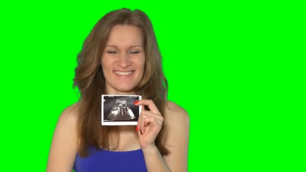 Těhotná žena dívka drží sonogram bříško, při pohledu na fotoaparát a s úsměvem. — Stock video