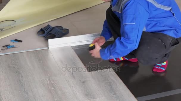 Man with ruler meter measure laminate length on floor — Stock Video