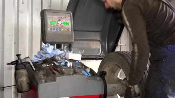 Técnico hombre que trabaja con la herramienta moderna de equilibrado de ruedas en el garaje — Vídeo de stock