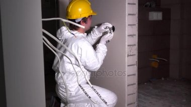 Elektrikçi montaj ışık anahtarı yuvası. Kask ve iş aşınma ile çalışan adam
