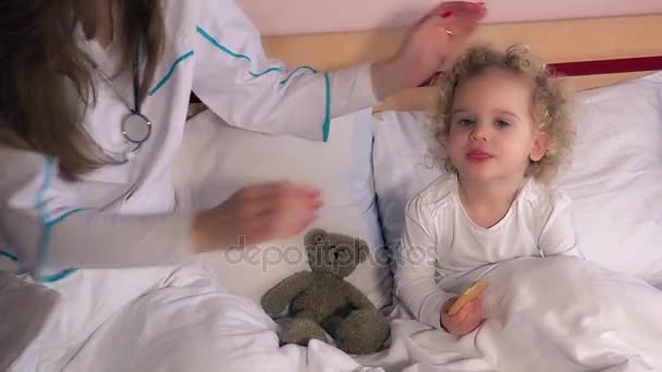 Niña en la cama haciendo chequeo médico pediatra chequeo de cabeza y garganta — Vídeo de stock