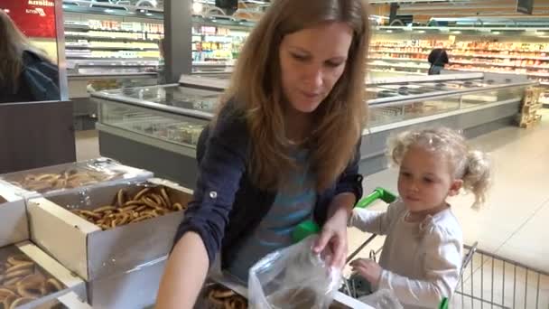 Mère enceinte et petite fille cueillant des biscuits au bagel sur le marché du shopping — Video