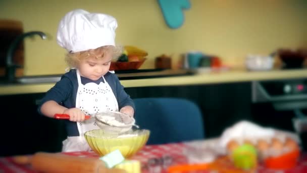 Adorable kitchen chef girl sifting flour for cake — Stock Video