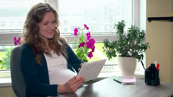 Ευτυχισμένη γυναίκα έγκυος χρησιμοποιώντας υπολογιστή tablet στο χώρο εργασίας — Αρχείο Βίντεο