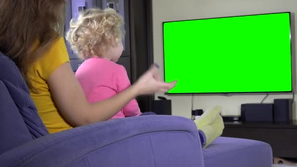 Little kid watching TV program with mom. Green chroma key screen — Stock Video