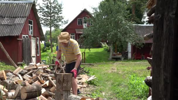 失敗した帽子を持つ農夫男は、大きな木製の丸太をチョップしようとします。4 k — ストック動画
