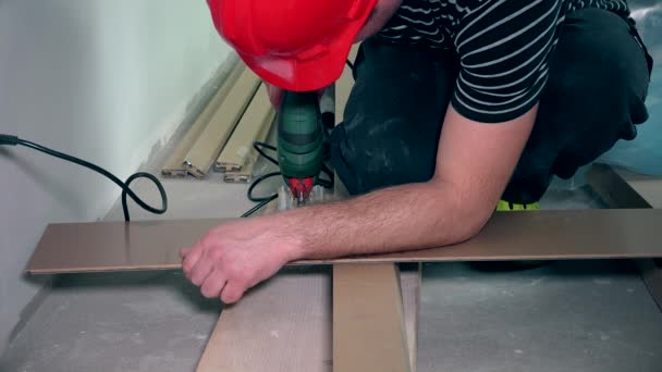 Mannelijke handen snijden parket vloer bord met decoupeerzaag — Stockvideo