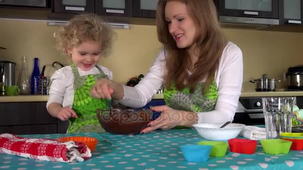 Speelse moeder met schattig kind meisje proeven van chocolade deeg uit de vinger en kus — Stockvideo