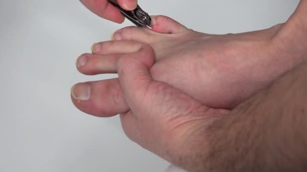 Руки делают педикюр с режущим инструментом на ногах с длинными ногтями — стоковое видео