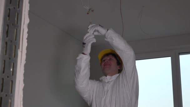 Электрик со шлемом откручивает лампочку — стоковое видео