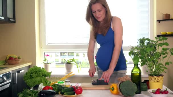 Mutfak masasının üzerinde özel kalemtıraş ile bıçak bileme hamile ev kadını. — Stok video