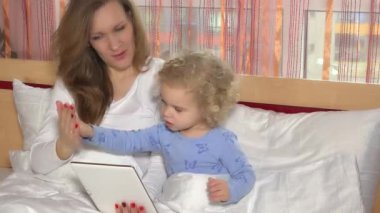 Anne ile evde yatakta yatarken ve dijital tablet seyir tatlı kız