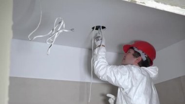 Alçıpan tavan aydınlatma enstalasyonu için delikleri yapma kalifiye erkek işçi