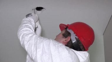 Alçıpan tavan aydınlatma enstalasyonu için delikleri yapma adam