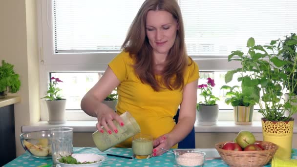 Щаслива майбутня мати готує фруктовий коктейль і п'є його, дивлячись на камеру — стокове відео