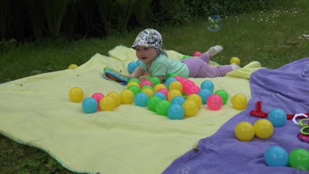 Happy baby enjoy flying soap bubbles on meadow. 4K — стоковое видео