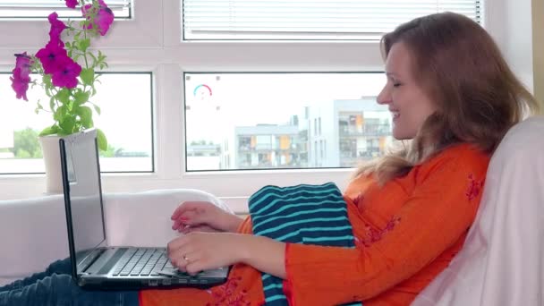 Mulher grávida com computador portátil e cartão de crédito compras roupas de bebê on-line — Vídeo de Stock