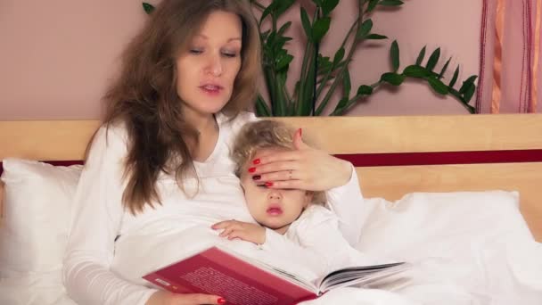 Мама читает сказку своей очаровательной дочери в спальне — стоковое видео